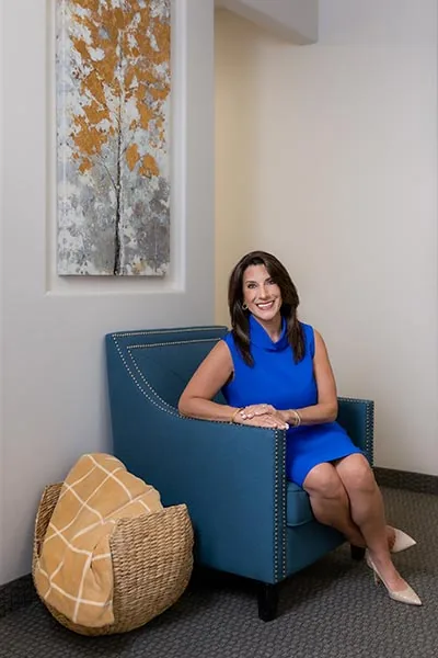 Woman in blue dress seated in modern clinic waiting area
