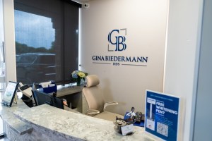 Gina Biedermann DDS reception desk with logo on wall