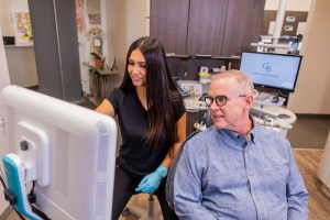 Dental assistant reviewing scan with patient in exam room